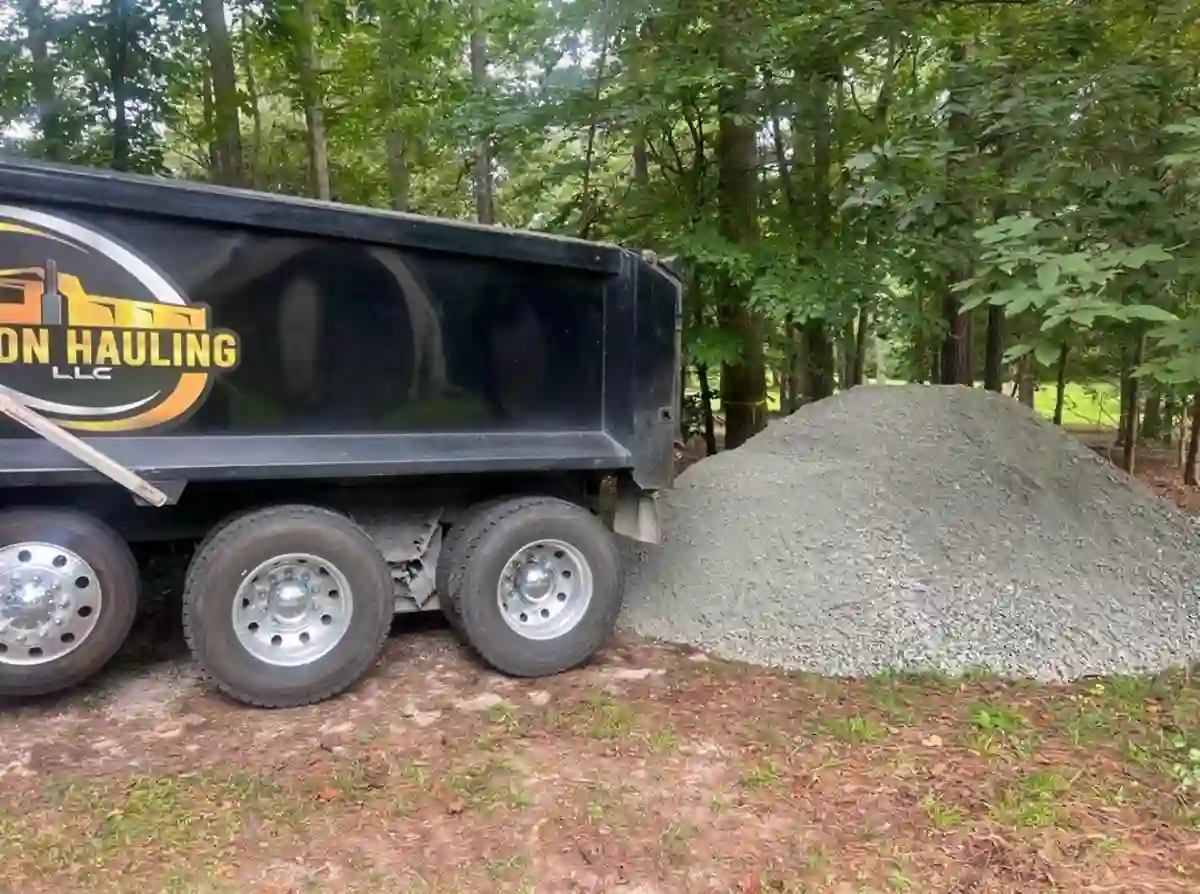 Johnson Hauling dump truck next to a freshly delivered gravel pile