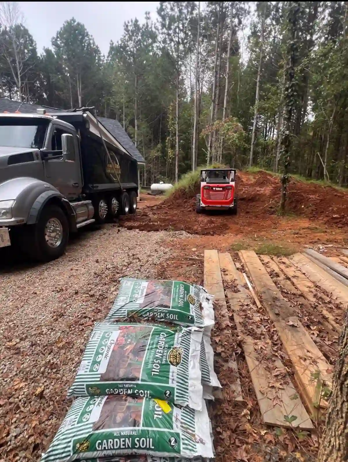 Johnson Hauling dump truck and skid steer moving dirt on a job site